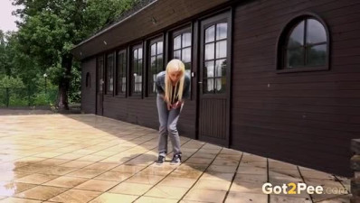 Stylish blonde amateur pulls down her pants and pees behind a house